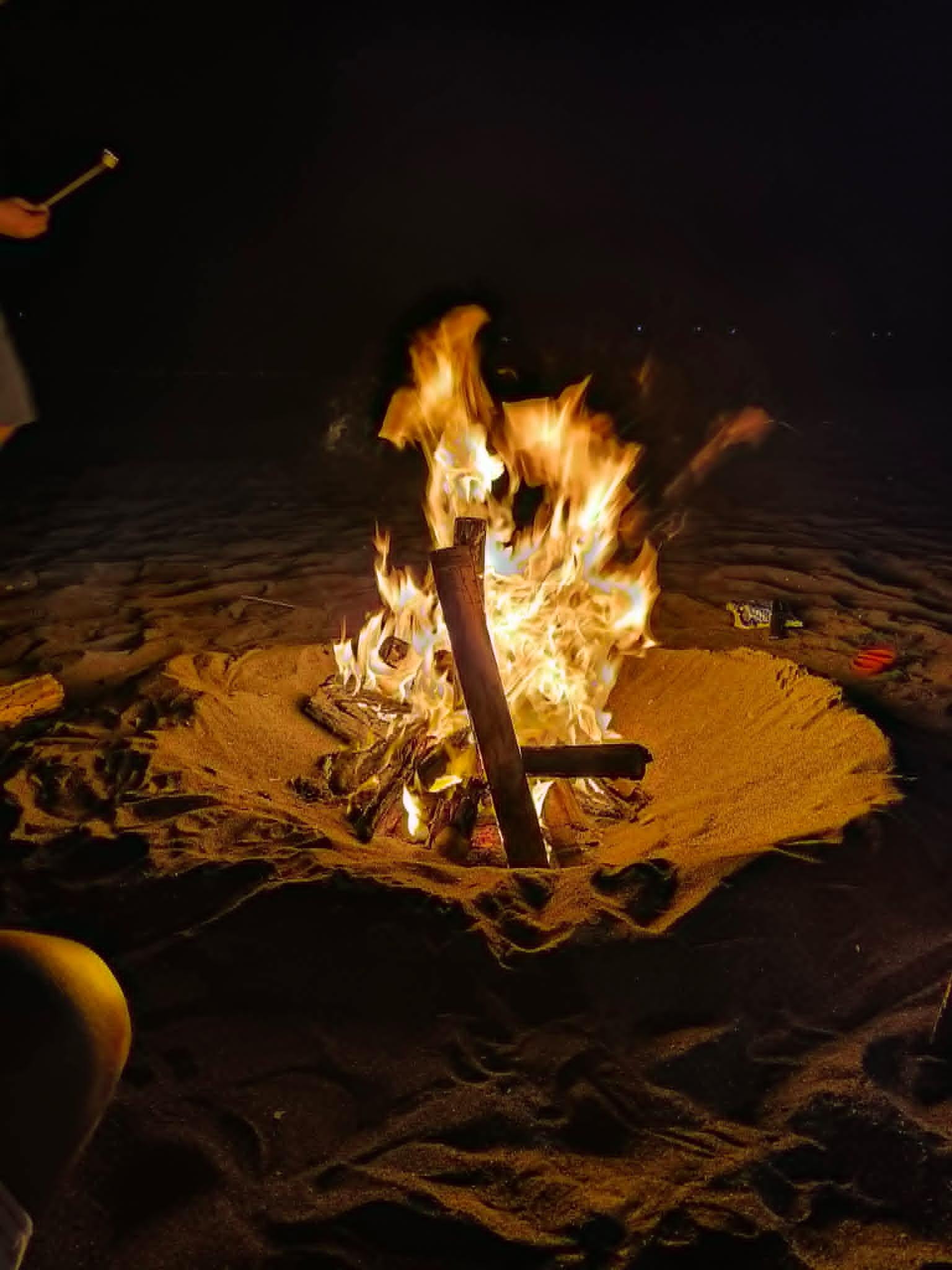 A warm bonfire glowing on the beach after sundown