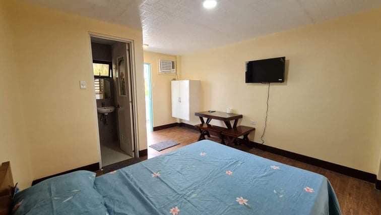 Air-conditioned Your Resort guest room with a double bed, wardrobe, wall-mounted TV, and door to the en-suite bathroom